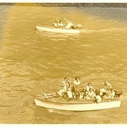 Uitzwaaiers dobberen in kleine bootjes rondom het grote schip.    