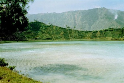 Het pad naar het Diengplateau voert langs een zwavelmeer, dat een stevige hoeveelheid H2SO4 uitstoot. Kleine teugjes adem nemen is het devies. En intussen toch proberen te genieten van de wonderlijk mooie groene kleur van het water.