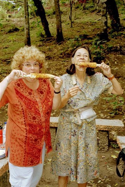 Aan de ingang van de waterval is koffie te koop en roosteren ze mais (jagung). Martine (links) en Maja genieten.