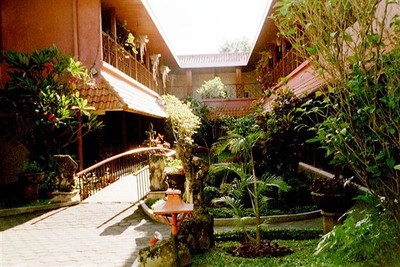 Hotel Puri Artha in Yogyakarta. De kamers liggen in een carré rond een tuin waarin een waterweg is aangelegd met rustieke bruggetjes er overheen.    