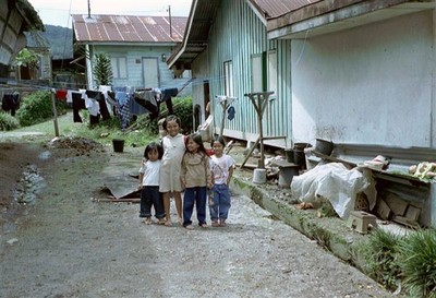 Vier kinderen spelen op een kaal stukje grond tussen de huizen en komen nieuwsgierig aanlopen. Mag ik een foto nemen?    
