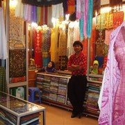In de bazaar is een winkelgalerij vol van de prachtigste sjaals en japonnen in felle kleuren. De Indiase eigenaar van één van de winkels poseert trots.