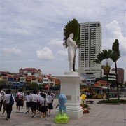 Raffles op de plek waar hij in 1819 aan land kwam. De schoolkinderen hebben zich met hem laten fotograferen. Achter het beeld een Travellers Palm, waaiervorming.