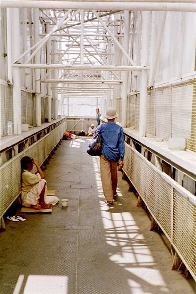 Tunjungan is te druk om er als voetganger over te steken. Hier en daar zijn loopbruggen gemaakt. Een mooie plek voor bedelaars. Zij hebben een taak in de moslim-gemeenschap: ze geven de gelovigen de kans om goed te doen.    