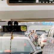 File op de snelweg op de vroege zaterdagochtend. Bedelaars en verkopers van koekjes begeven zich langs de stilstaande auto's om wat handel los te wrikken.    