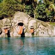 Het zwembad van Puri Asri met drie enorme stenen monsterkoppen. Soms spugen ze een lachende kleuter uit. Ze zijn het eind van een glijbaan.    