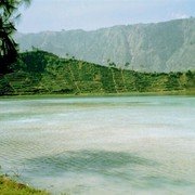 Het pad naar het Diengplateau voert langs een zwavelmeer, dat een stevige hoeveelheid H2SO4 uitstoot. Kleine teugjes adem nemen is het devies. En intussen toch proberen te genieten van de wonderlijk mooie groene kleur van het water.