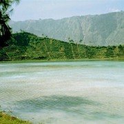 Het pad naar het Diengplateau voert langs een zwavelmeer, dat een stevige hoeveelheid H2SO4 uitstoot. Kleine teugjes adem nemen is het devies. En intussen toch proberen te genieten van de wonderlijk mooie groene kleur van het water.    