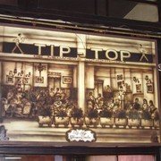 Binnen hangt een reclame-tekening in sepia-tinten waarop te zien is hoe hier ooit grote koloniale gezelschappen bezig waren vrolijk te zijn