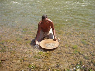 De mengeling van zand en water in de schaal begint te draaien. De lichte zandkorrels lopen over de rand van de schaal weer de rivier in, terwijl het zwaardere goudpoeder bezinkt. Als hij dit twee dagen doet heeft hij 1 gram goud, daar krijgt hij 2 euro voor.