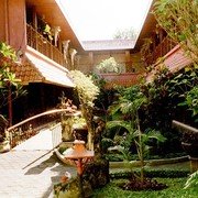 Hotel Puri Artha in Yogyakarta. De kamers liggen in een carré rond een tuin waarin een waterweg is aangelegd met rustieke bruggetjes er overheen.    