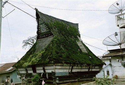 Authentieke Karo-Batak-woning in Peceren bij Brastagi. Ingeklemd tussen stenen burgermanshuisjes, elk voorzien van een gigantische satellietschotel.