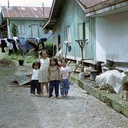 Vier kinderen spelen op een kaal stukje grond tussen de huizen en komen nieuwsgierig aanlopen. Mag ik een foto nemen?