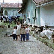 Vier kinderen spelen op een kaal stukje grond tussen de huizen en komen nieuwsgierig aanlopen. Mag ik een foto nemen?    