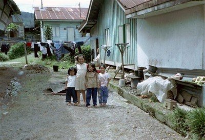 Vier kinderen spelen op een kaal stukje grond tussen de huizen en komen nieuwsgierig aanlopen. Mag ik een foto nemen?