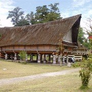 Het koningshuis van de Batak Simalungung. Op een open plaats in het bos staat een wel dertig meter lang huis op palen met een fraai puntdak.